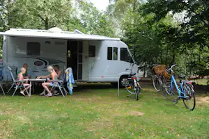 Camping 't Schinkel - Camper sitzen vor dem Wohnmobil im Schatten mit Zeltdach