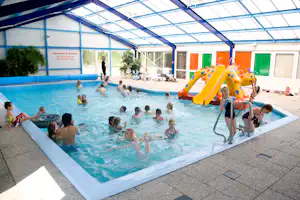 Kinderpool im Hallenbad mit aufblasbarem Spielgerät, Sonnenschutzdach und bunten Türen im Hintergrund.
