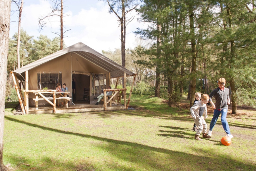 Camping 't Zand - Kinder spielen Fußball auf der Wiese vor einem Glamping-Zelt