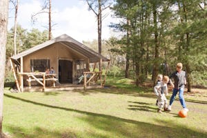 Camping 't Zand - Kinder spielen Fußball auf der Wiese vor einem Glamping-Zelt