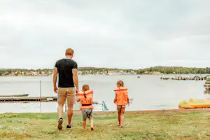 Camping Tättö Havsbad - Vater mit Kindern auf dem Weg zum Badestrand am See