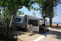 Camping Thines - ein Wohnwagen im Schatten der Bäume mit dem Strand und Mittelmeer im Hintergrund