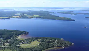 Weitblick auf einen See von oben, mit bewaldeten Ufern, kleinen Buchten und einem schmalen Landstreifen.