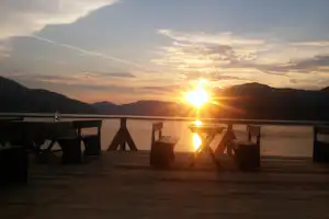 Terrasse mit Sitzbaenke des Camping Toma an der Donau bei Sonnenuntergang