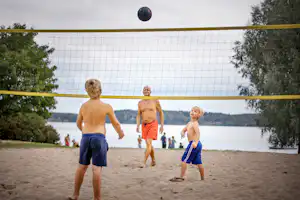 Nordic Camping Nora - Camper spielen Beach-Volleyball am Strand auf dem Campingplatz