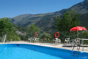 Camping Trevélez - Pool vom Campingplatz mit Stühlen in der Sonne und Blick auf die Berge vom Nationalpark Sierra Nevada