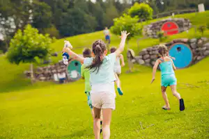 Camping- und Ferienpark Orsingen - spielende Kinder auf grüner Wiese vom Campingplatz, Mobilheime im Hintergrund