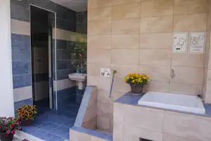 Modernes Badezimmer mit Badewanne, Waschbecken und Dusche, gefliestem Boden und Wandfliesen in Blau und Beige.