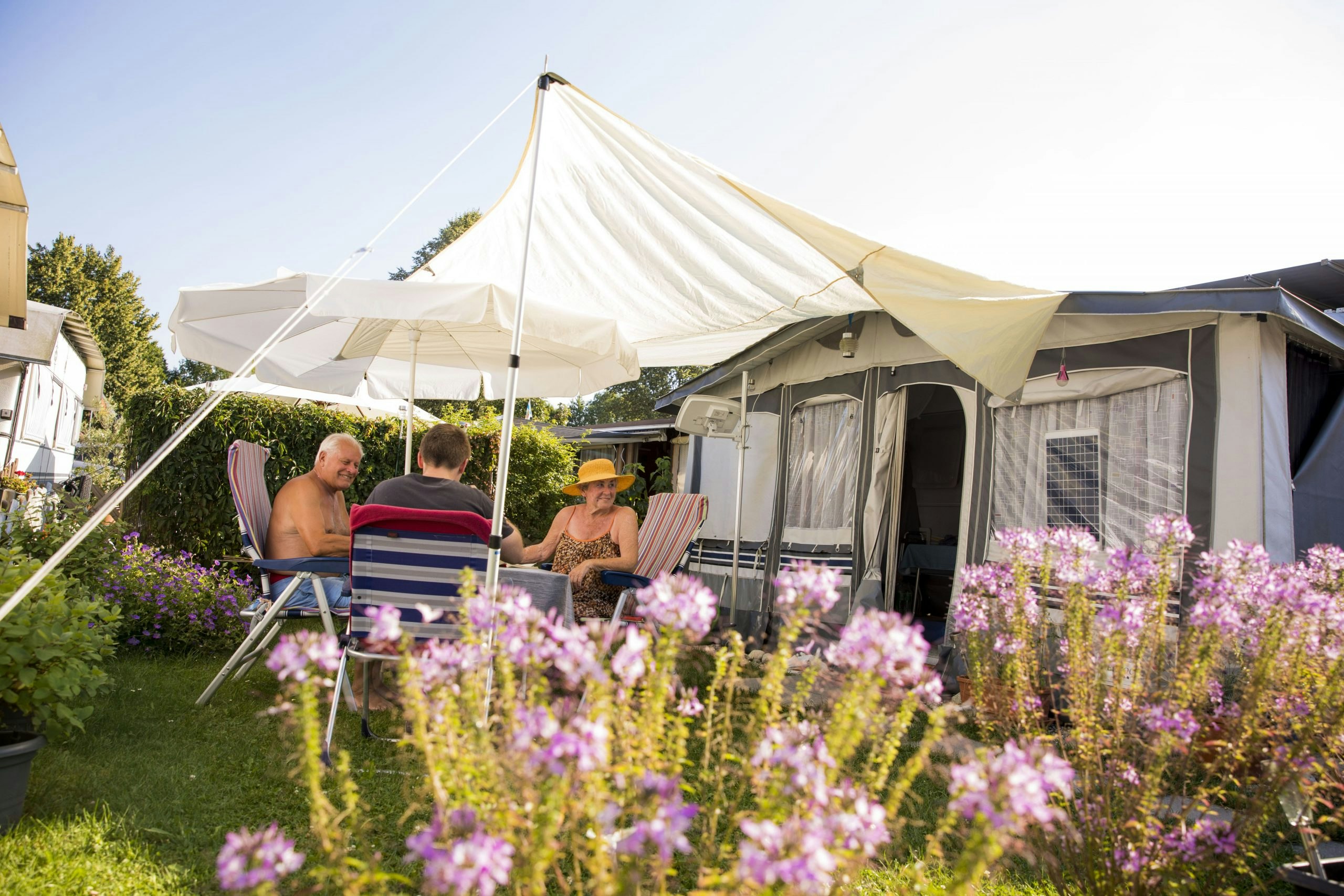 Campingplatz Utting am Ammersee - Camper sitzen vor ihrem Wohnwagen auf einem Standplatz