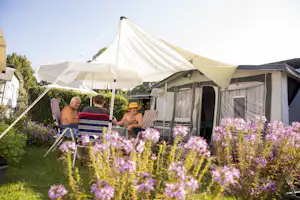 Campingplatz Utting am Ammersee - Camper sitzen vor ihrem Wohnwagen auf einem Standplatz
