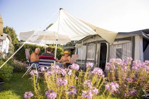 Campingplatz Utting am Ammersee - Camper sitzen vor ihrem Wohnwagen auf einem Standplatz