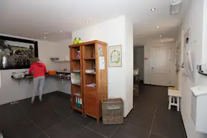 Innenraum eines Campinghauses mit Holzvitrine, weißem Flur, Sitzbank und Küchenzeile im Hintergrund.