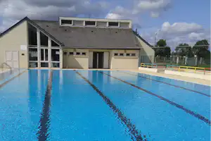Schwimmbecken auf einem Campingplatz mit Blick auf das Gebäude und den Zaun am Beckenrand.