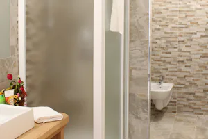Camping Val di Sole - Sanitärbereich mit Dusche, Waschbecken und Spiegel im Mobilheim