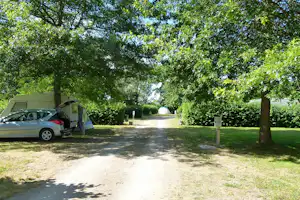 Camping Val Vert en Berry - Wohnwagenstellplätze auf grüner Wiese im Schatten der Bäume auf dem Campingplatz