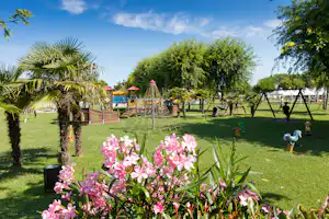 Camping Village Ca' Pasquali - Grünfläche mit Spielplatz und Bäumen