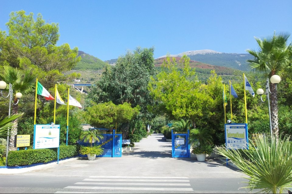 Camping Village International - Einfahrt vom Campingplatz mit Blick auf die Berge von Italien