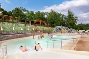 Beheizter Camping-Pool mit mehreren Personen im Wasser, Sonnenschirmen am Beckenrand und Holzterrasse im Hintergrund.