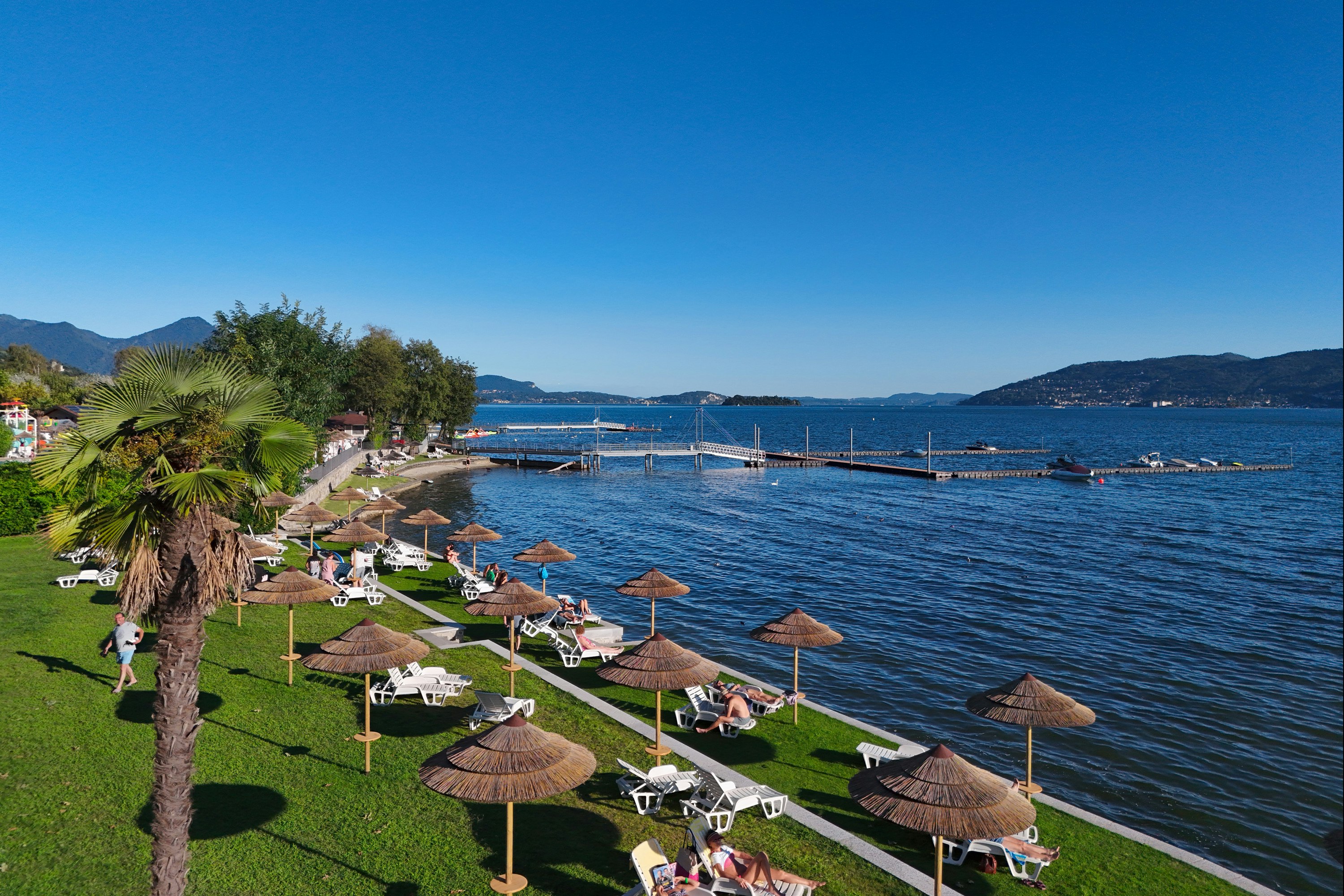 Camping Village Isolino - Badestrand mit Liegewiese und Liegestühlen auf dem Campingplatz