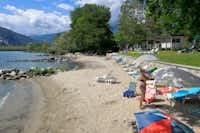 Camping Village Isolino - Blick auf den Strand mit Liegestühlen und Sonnenschirmen