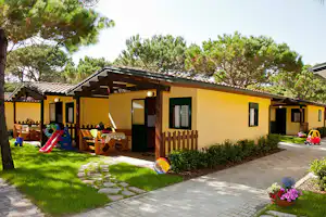 Camping Village Scarpiland - Außenansicht Mobilheime mit Kinderspielzeug auf Wiese im Schatten
