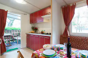 Camping Village Scarpiland - Esstisch und Küche mit anliegender Veranda in einem Mobilheim
