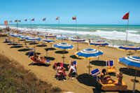 Camping Villaggio Baia Domizia  -  Strand mit Sonnenschirmen und Liegestühlen am Campingplatz