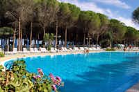 Camping Villaggio Thurium  -  Pool vom Campingplatz zwischen Bäumen mit Sonnenschirmen und Liegestühlen