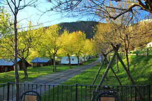 Camping Viu - Allee mit Bungalows und Wohnwagen an der Seite mit Schaukeln im Vordergrund