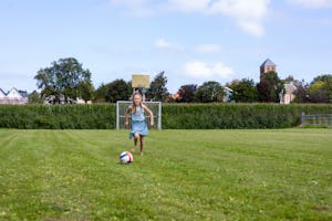 Camping Waddenzee - Kind spielt Fußball auf der Wiese