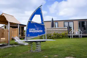 Camping Waddenzee - Kinderspielplatz mit Mobilheim im Hintergrund