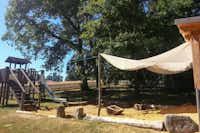 Camping Weichselbrunn - Kinderspielplatz mit Rutsche und Schaukel im Schatten unter Bäumen auf dem Campingplatz