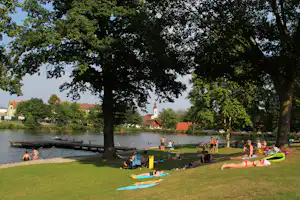 Camping Weinland - Liegewiese mit Bäumen und Badesee vom Campingplatz
