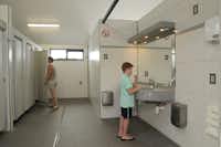 Camping Zavelbos - Innenraum des Sanitärgebäudes mit Duschkabinen und Wacshbecken mit Spiegeln