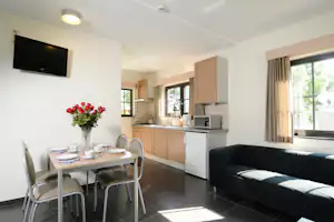 Camping Zavelbos - Innenraum eines Bungalows mit Couch, Esstisch und Kochecke