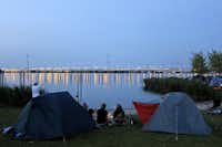 Camping Zeeburg - Camper sitzen abends bei ihren Zelten und blicken auf das IJmeer