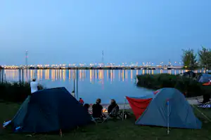 Camping Zeeburg - Camper sitzen abends bei ihren Zelten und blicken auf das IJmeer