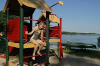 Camping Zwenzower Ufer  - Kind auf dem Spielplatz vom Campingplatz mit Blick auf den See
