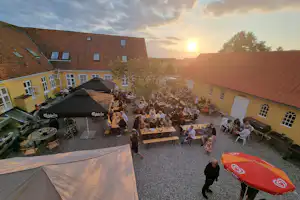 Campinggaarden Boeslunde - Außenterrasse auf dem Campingplatz mit Sonnenschirmen und Picknickbänken