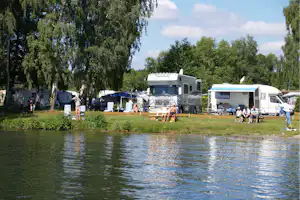 Campingpark Kamerun - Gäste am Wasser vor den Wohnmobilstellplätzen im Grünen auf dem Campingplatz