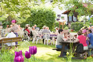 Campingpark Schellental - Camper auf der Terrasse vom Restaurant auf dem Campingplatz zwischen Bäumen