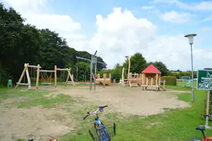 Campingpark Schlei-Karschau - Kinderspielplatz mit Schaukeln neben Bäumen auf dem Campingplatz