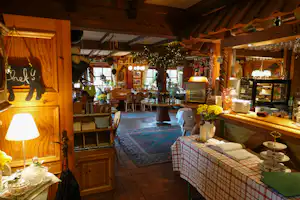 Holz-Lounge mit Bar und Theke, Gläsern und Flaschen, Sitzgelegenheiten und Tischdecke im Innenbereich eines Campingplatzes.