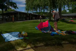 Campingplatz Allensbach - Camper beim Sonnenbaden mit Gebäude des Campingplatzes im Hintergrund