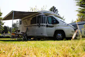 Campingplatz Am Furlbach - Campingbestuhlung unter dem schattenspendenden Vordach eines Wohnmobils auf der Wiese des Campingplatzes