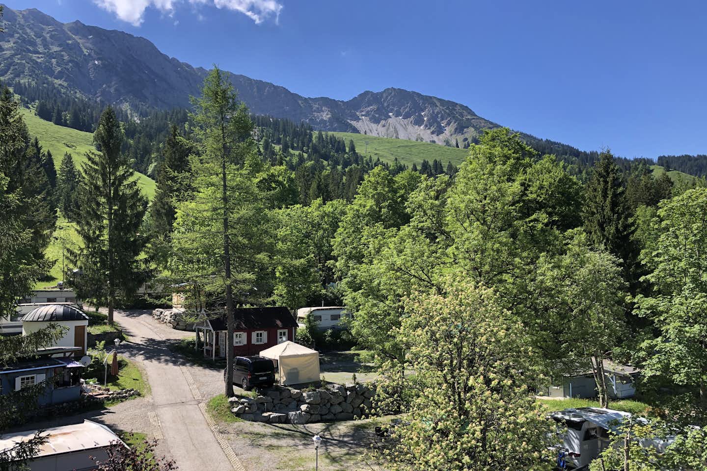 Camping und Pension Bergheimat Blick von einer Anhöhe auf die Standplätze und Mietunterkünfte mit Bergen im Hintergrund  