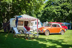 Campingplatz der Stadt Köln - Gast im Schatten unter seiner Pagode vor dem Wohnwagen im Grünen auf dem Campingplatz