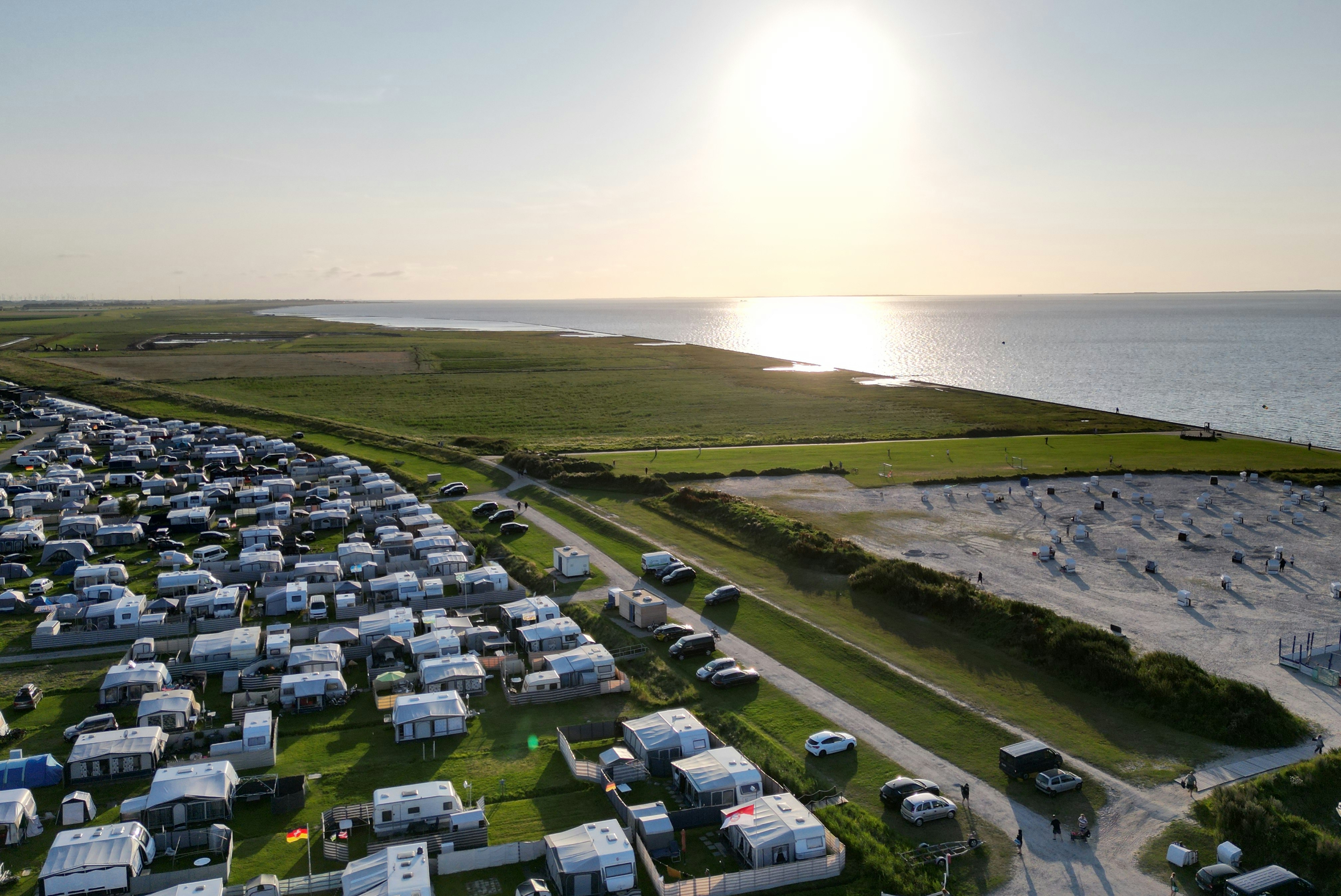 Campingplatz an der Küste mit Wohnwagen und Stellplätzen, Weg zum Strand und Blick aufs Meer.