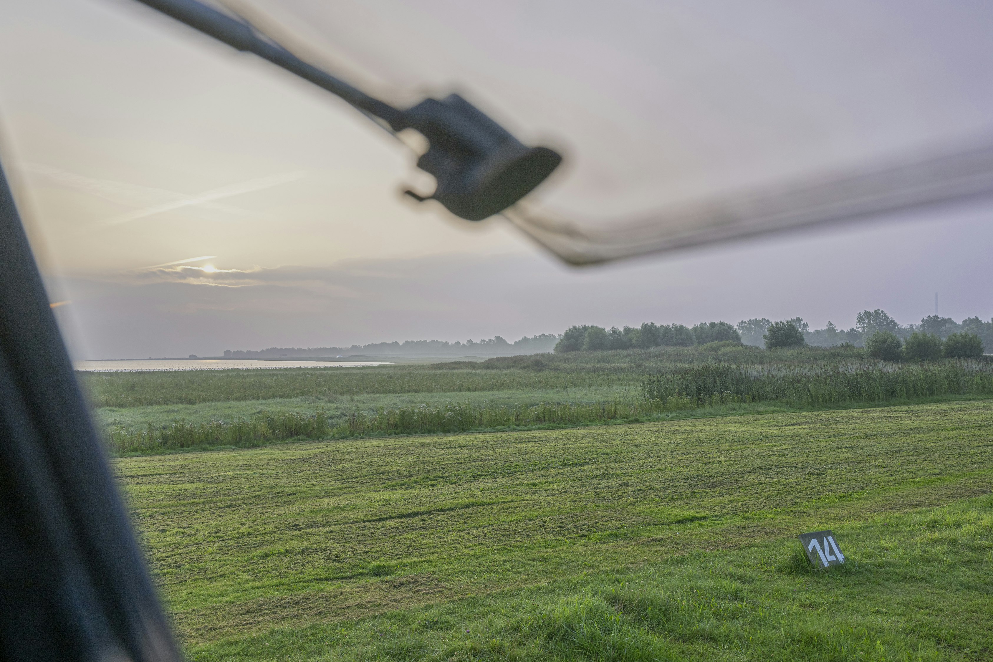 Campingplatz Hooksiel - Blick aus einem Wohnwagen auf die Standplatzwiese und die weitläufige grüne Landschaft