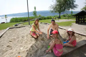 Campingplatz Horn - Familie im Sandkasten auf dem Spielplatz vom Campingplatz mit Blick auf den See